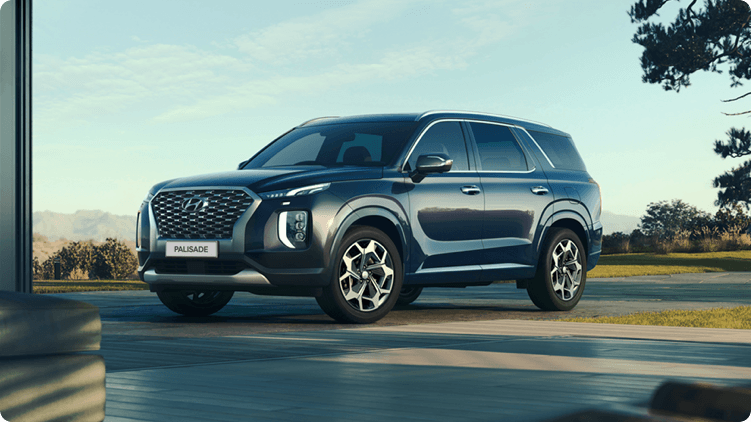 A Hyundai Palisade SUV parked  in front of a very expensive house.